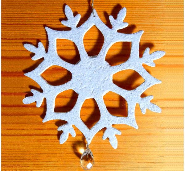 White flax felt decoration snowflake, with crystal stone, on log wall.